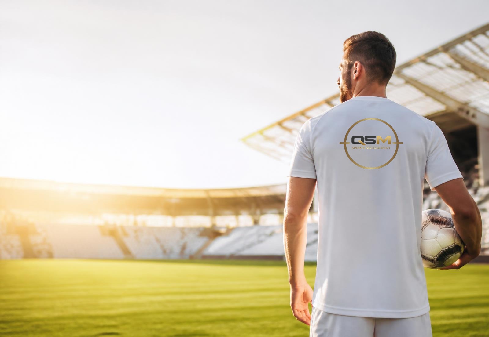 Professional footballer wearing a QSM Sports Management shirt in a stadium